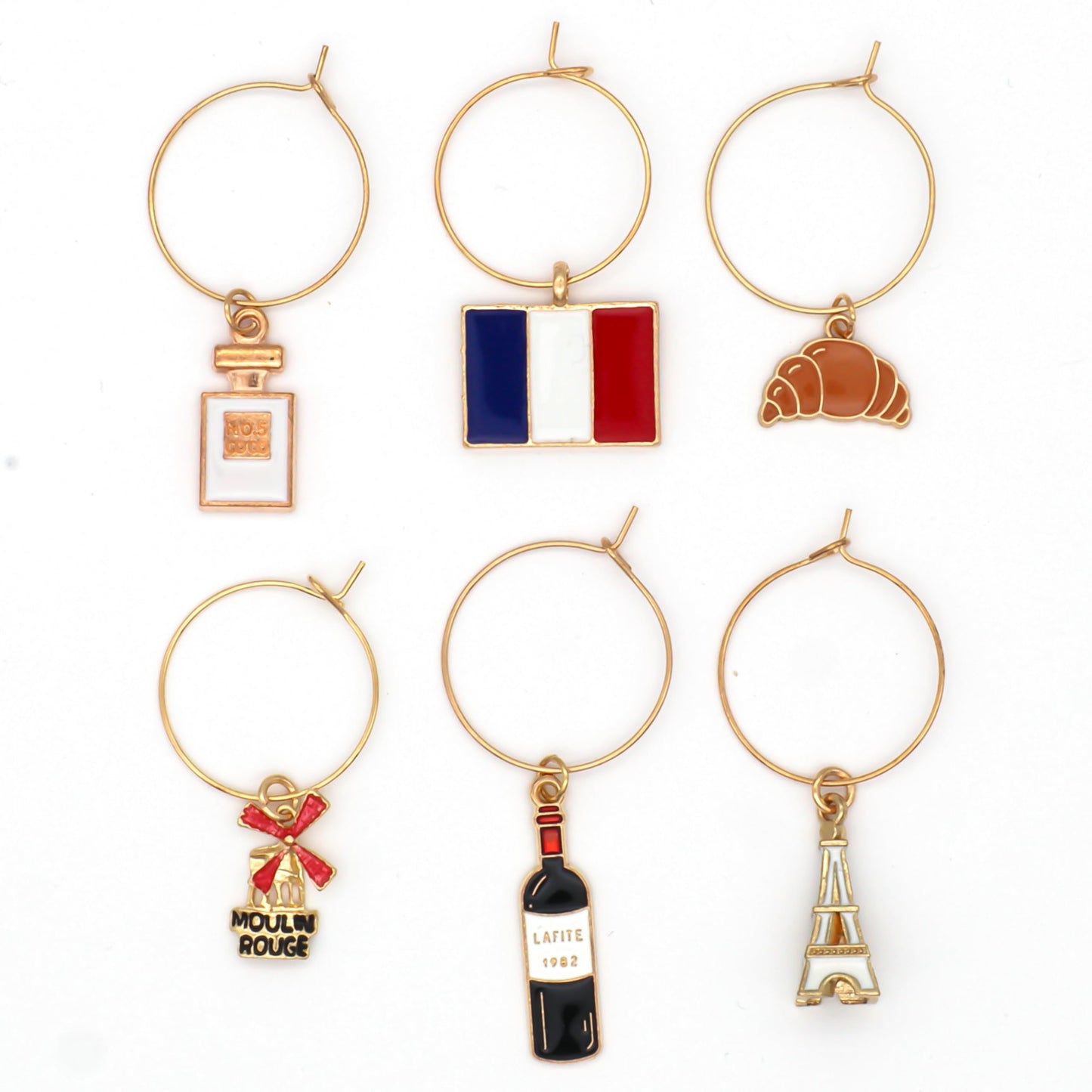 A set of French Wine Charms including the Flag of France, Eiffel Tower, Crossaint, Moulin Rouge, French Wine and Perfume on the white surface.