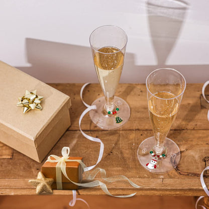 A set of Christmas Wine Charms hooked on wine glasses on wood surface with Christmas decoration.