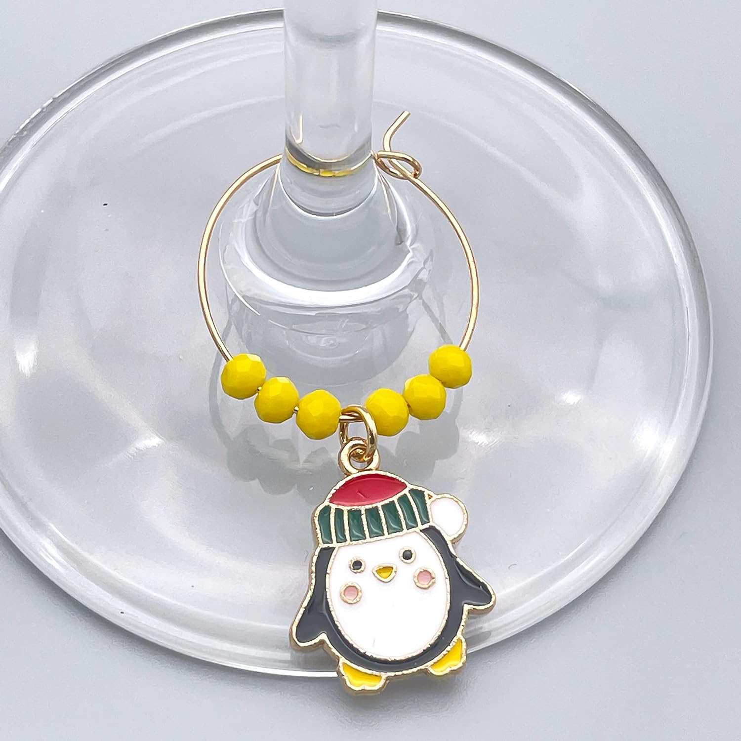 A Penguin Winter Wine Glass Charms hooked on the glass.