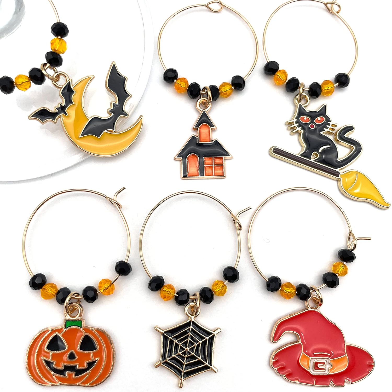 Halloween Wine Charms set of witch hat, bat, spider web, jack-o'-lanterns, and black cat on a white surface.