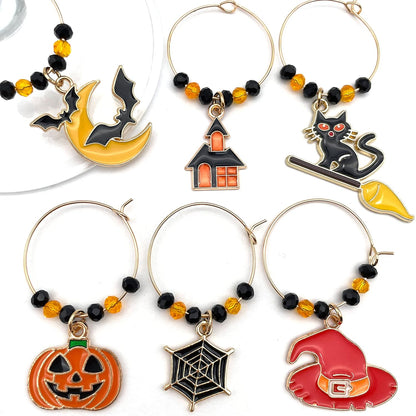 Halloween Wine Charms set of witch hat, bat, spider web, jack-o'-lanterns, and black cat on a white surface.