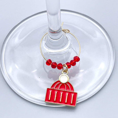 A Red Christmas Hat Winter Wine Glass Charms hooked on the glass.