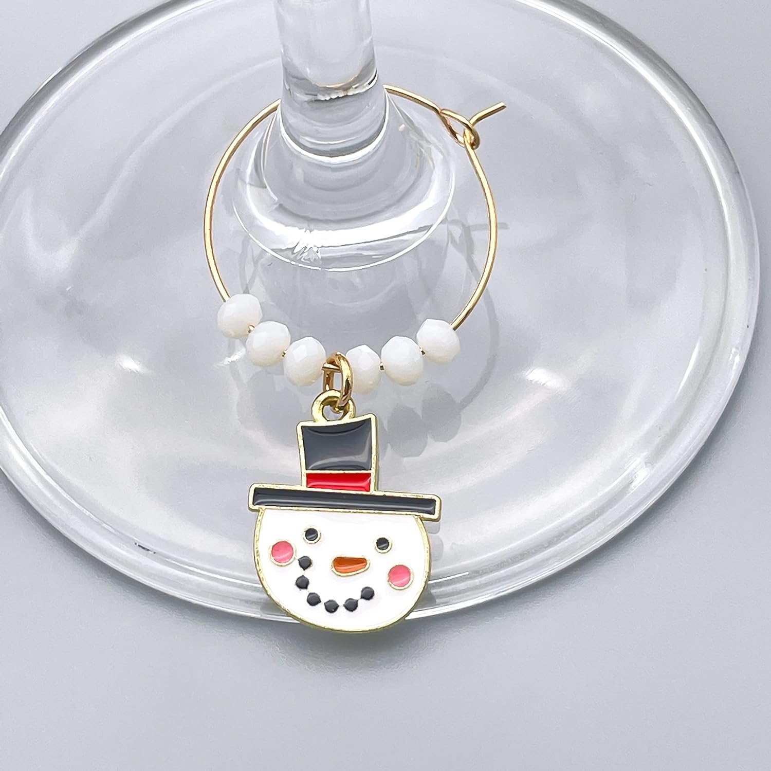 A White Snowman Winter Wine Glass Charms hooked on the glass. 