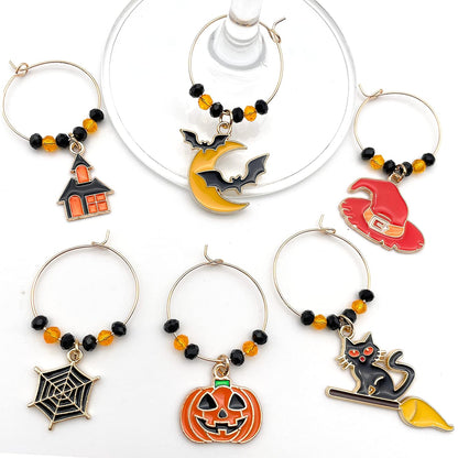 Halloween Wine Charms set of witch hat, bat, spider web, jack-o'-lanterns, and black cat on a white surface.