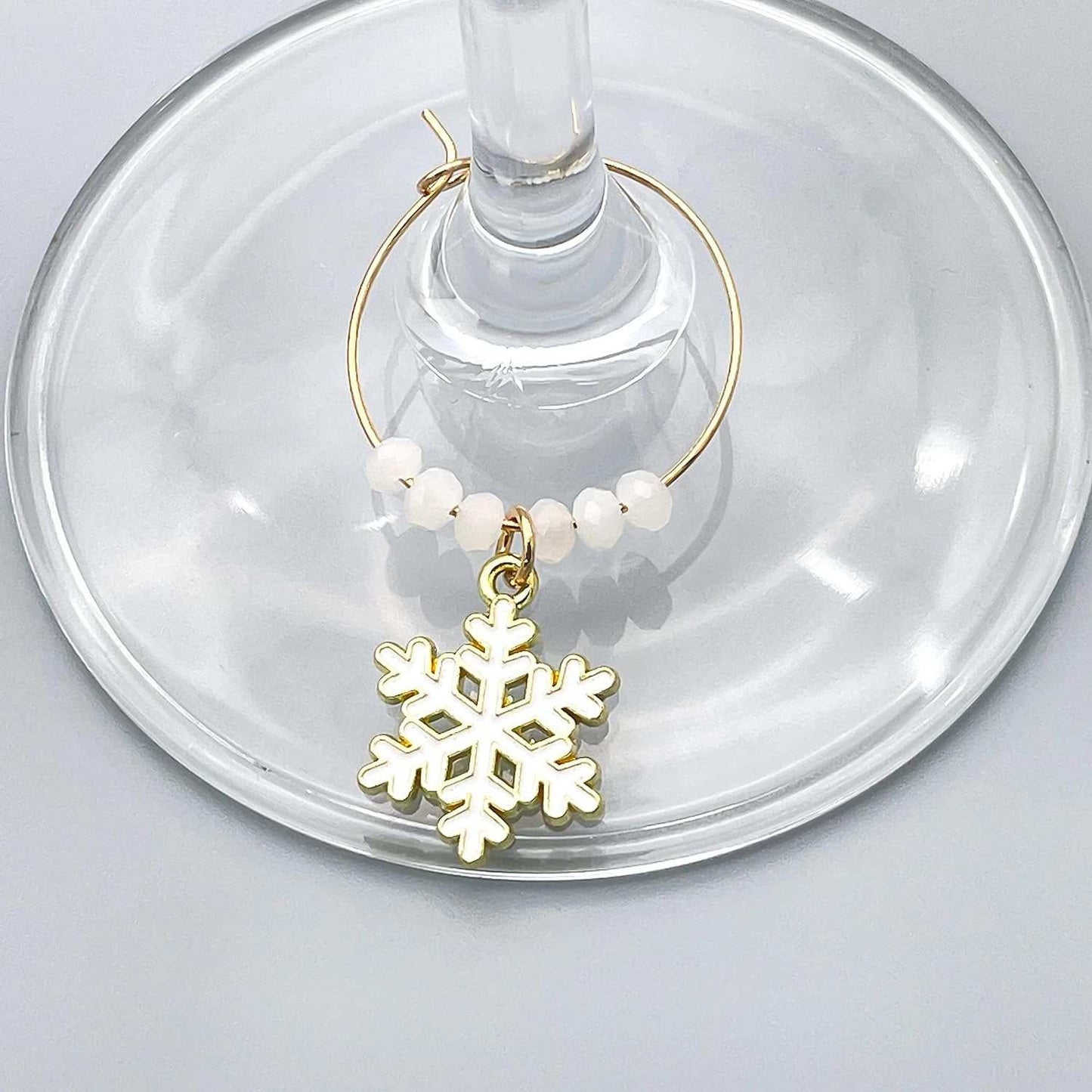 A white Snowflake Winter Wine Glass Charms hooked on the glass.