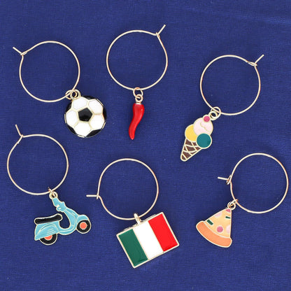 Italian Wine Charms set includes Italian Flag, Vespa, Soccer Ball, Gelato, Red Wine Glass, and Italian Horn on a blue surface