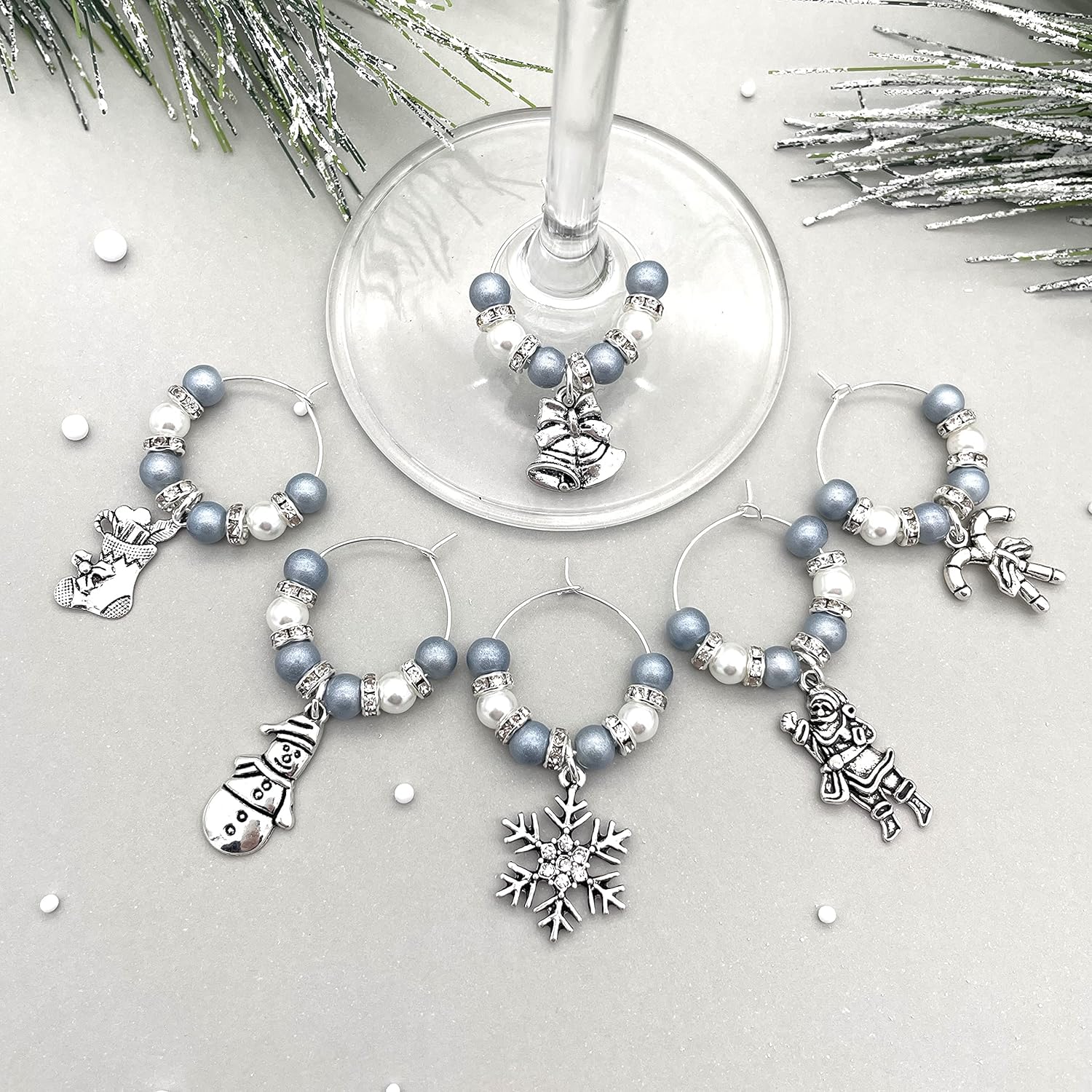 Christmas Wine Glass Charms, Set of 6, Charms Include: Snowman, Ski, Mitttens, Shawl, Snowflake, Deer on a gray surface