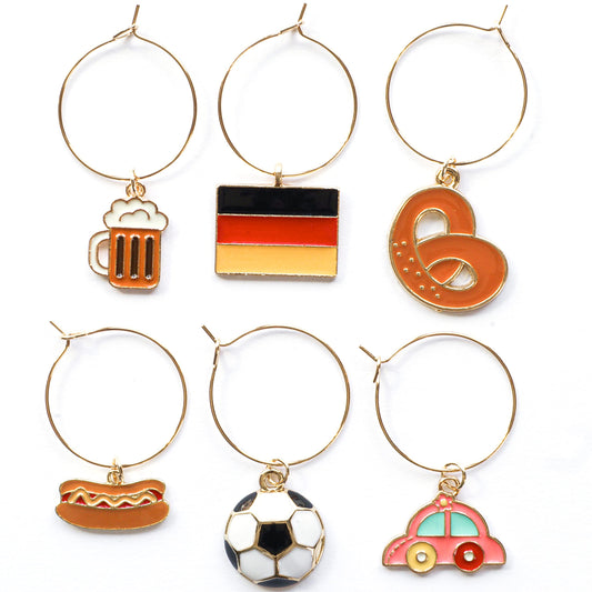A set of Germany Wine Charms featuring Flag of Germany, Beer Mug, Pretzel, Car, Soccer Ball and Sausage on a white surface.