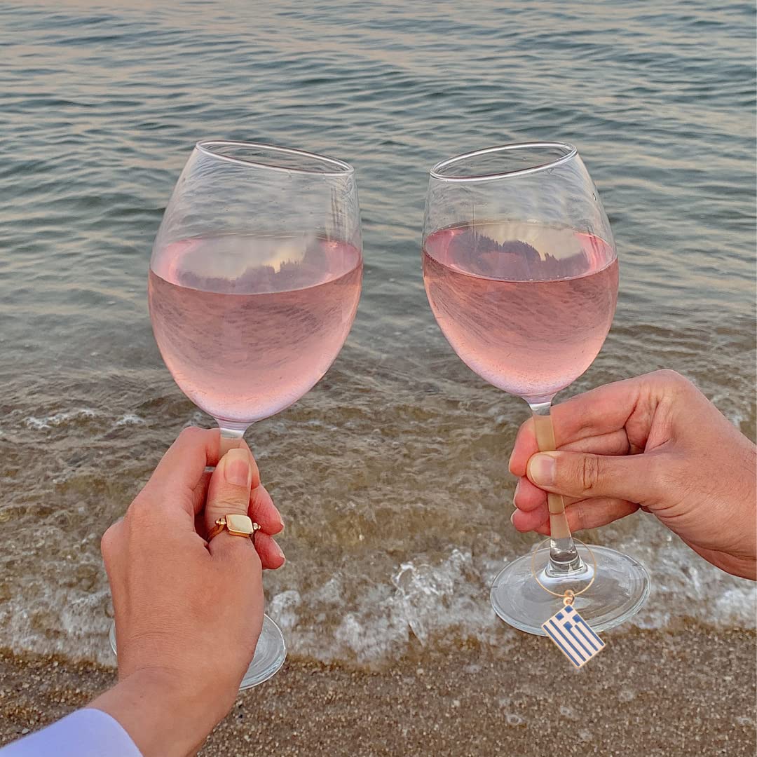 A woman and a man holding glasess with Greek Wine Charms.