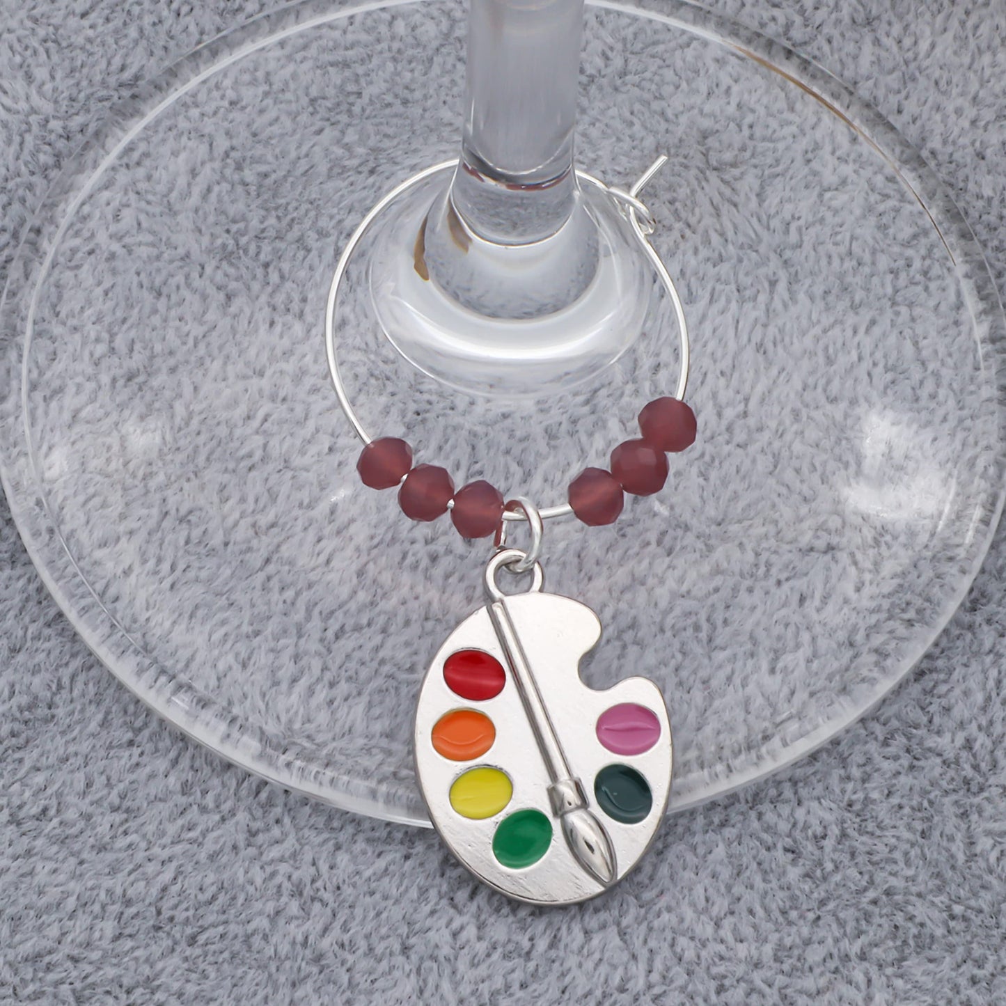 A painting Favorite Teacher Wine Glass Charms hooked on the glass.