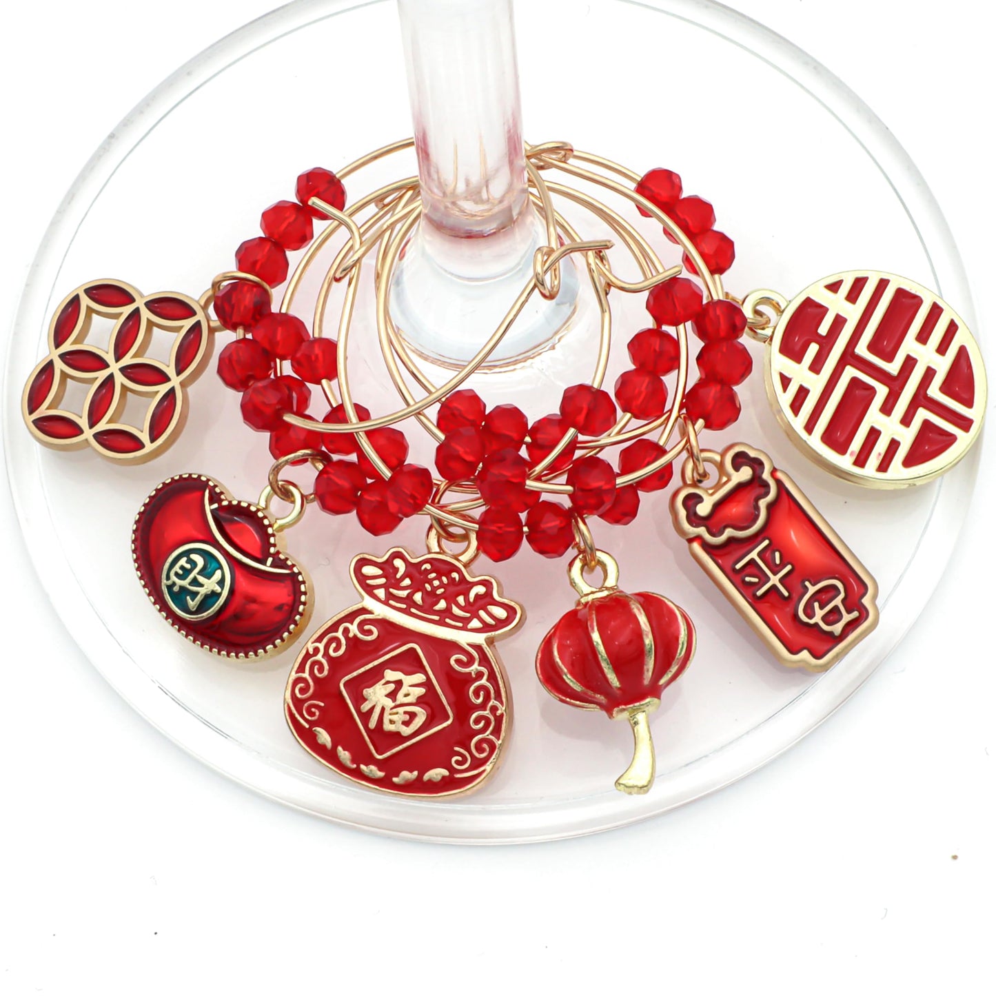 Red-Colored set of Chinese New Year Wine Charms hooked on wine glass.