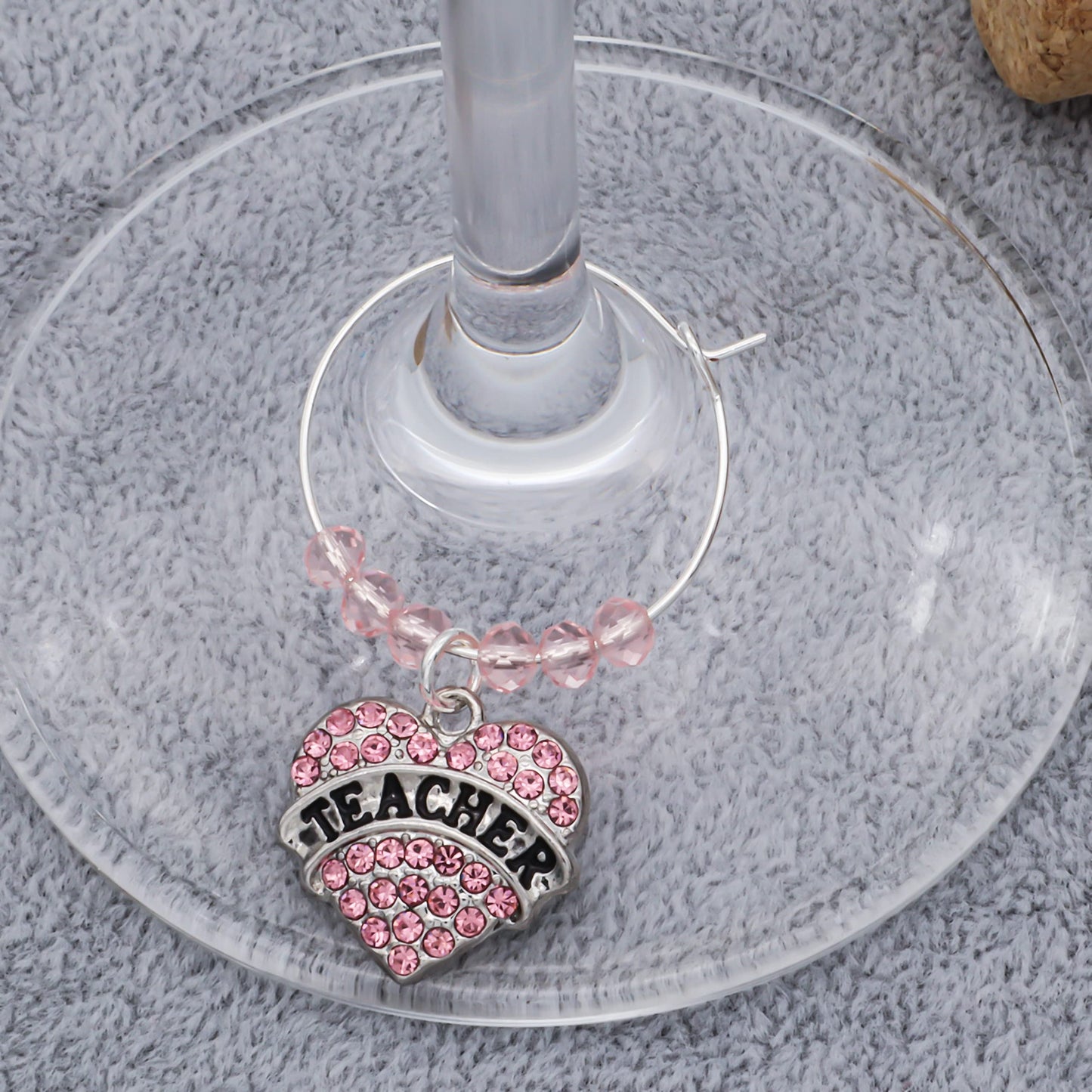 A Favorite Teacher Wine Glass Charms hooked on the glass.